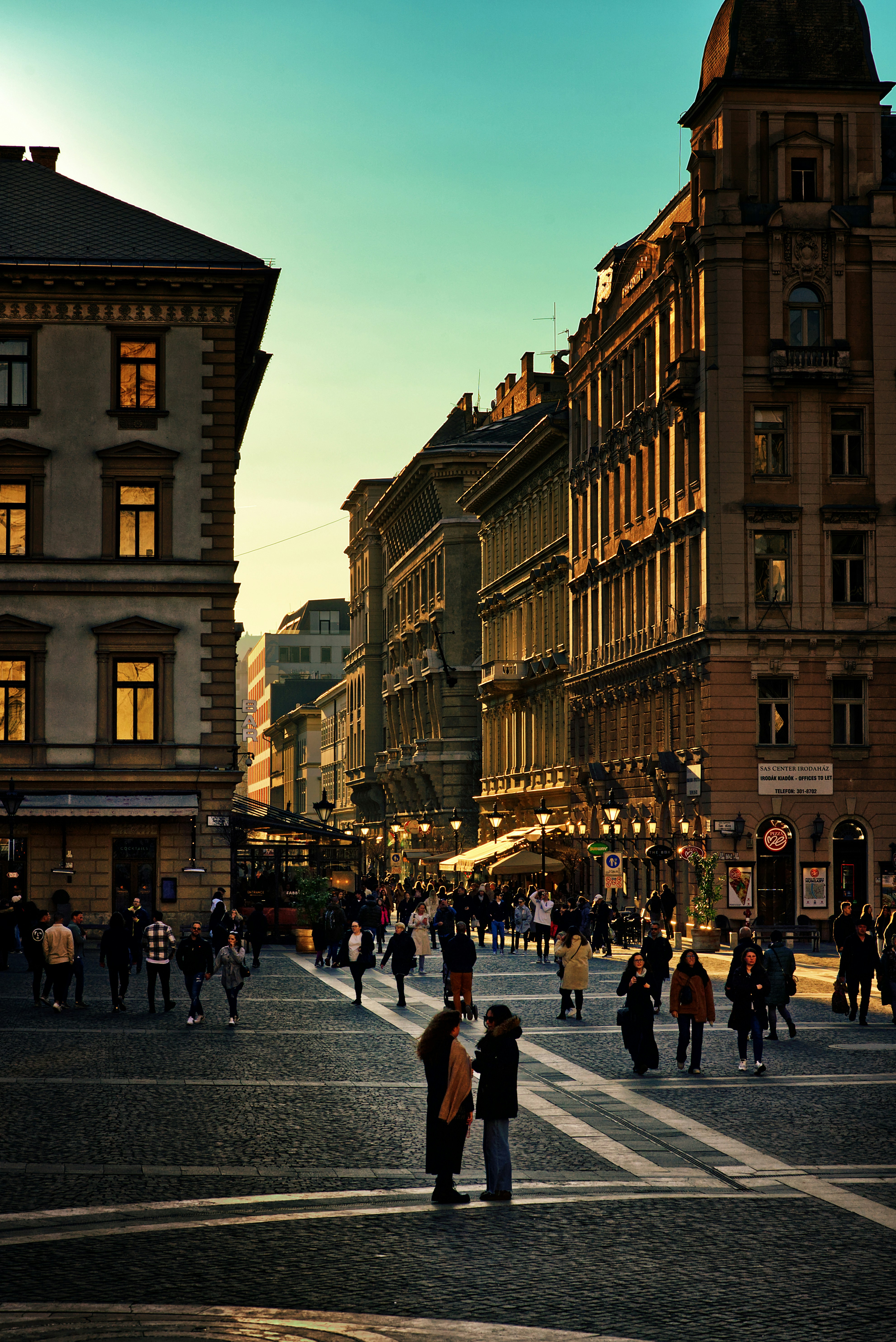 Budapest utca aranyórában, sétáló emberek
